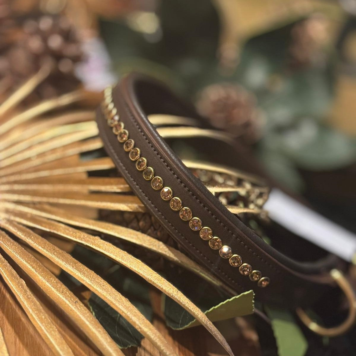 Brown leather padded dog collar with rose gold studs on a decorative background