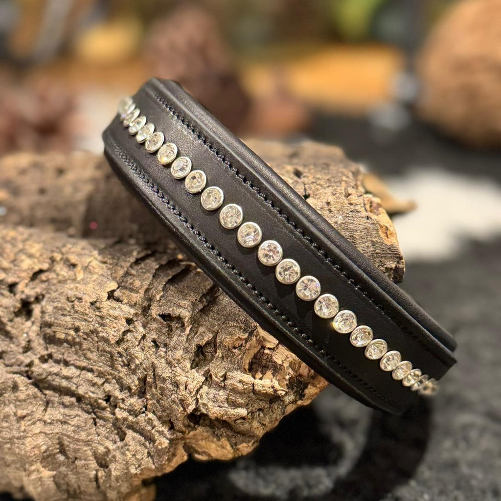 Black leather dog collar with clear crystal studs on a decorative background