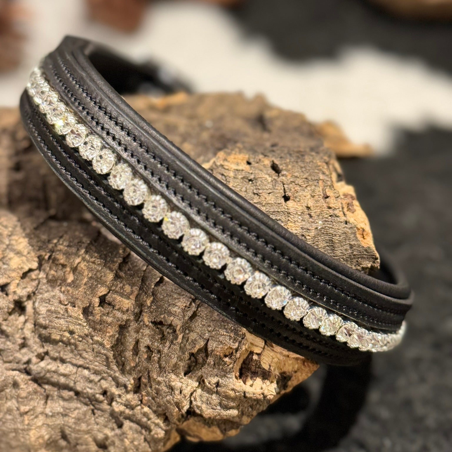 Black leather dog collar with clear crystal rhinestones detailing on a textured surface