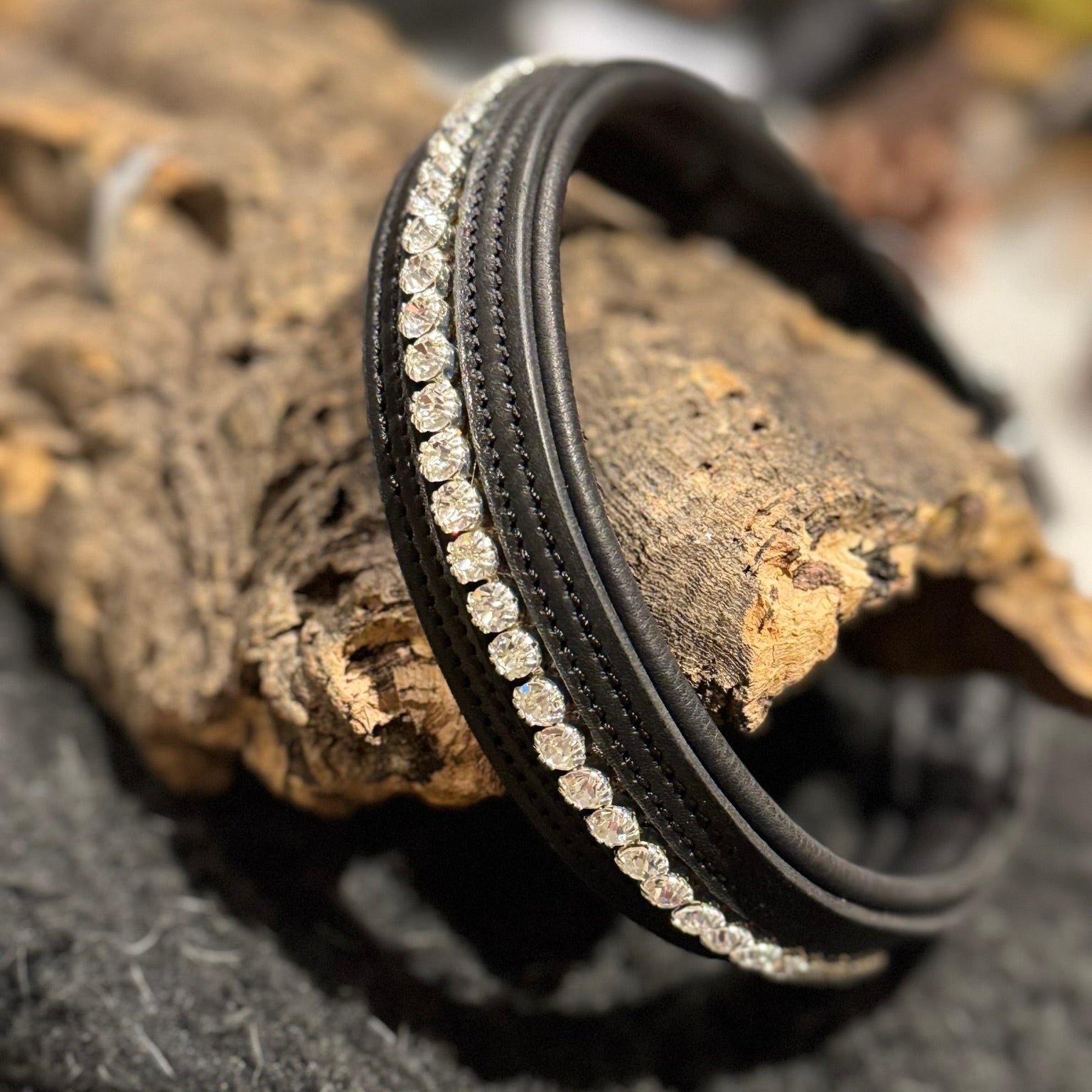 Black leather dog collar with clear crystal rhinestones detailing on a textured surface
