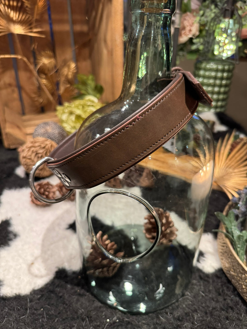 Glass bottle with a brown leather dog collar hanging on it 