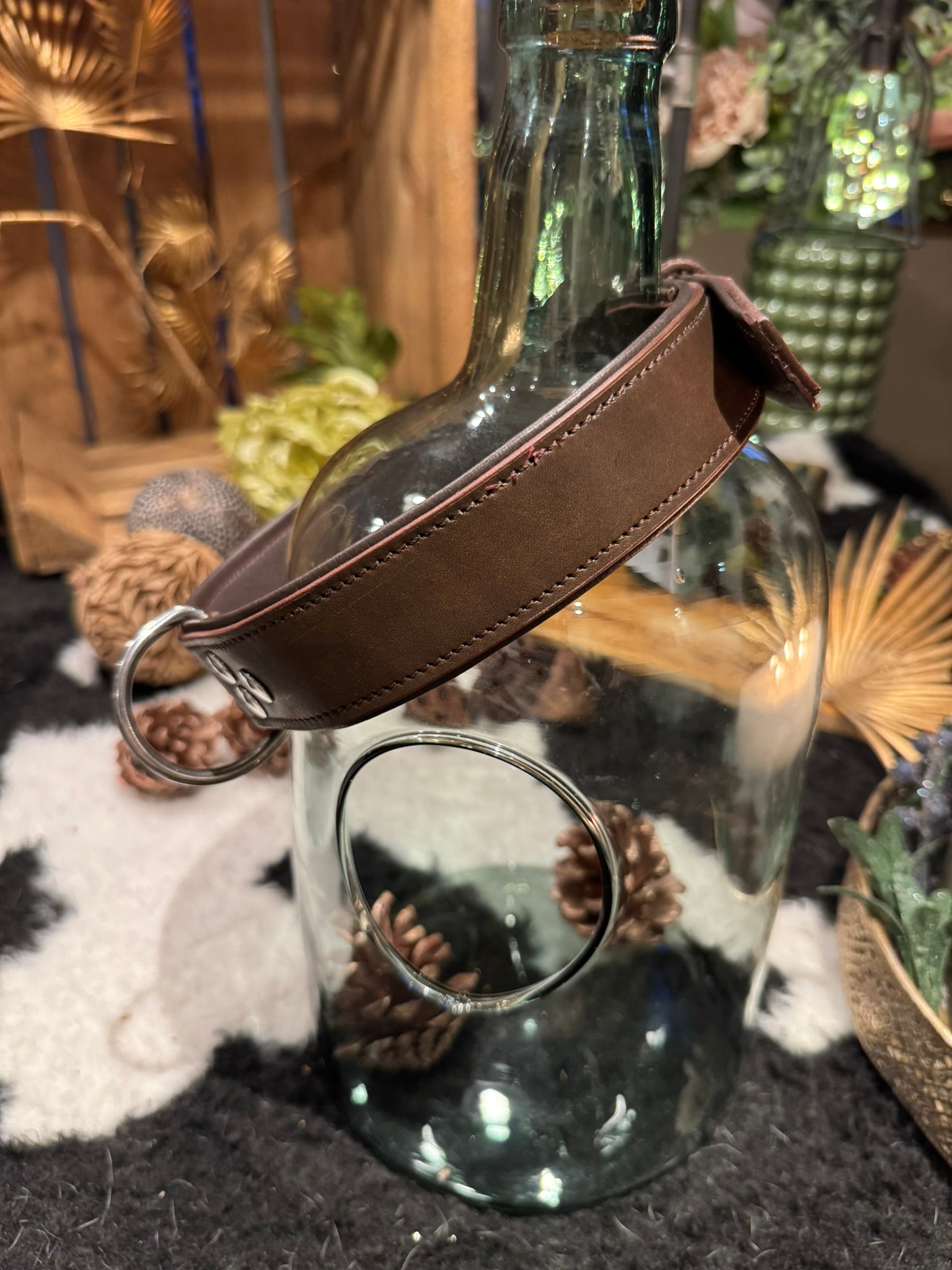 Glass bottle with a brown leather dog collar hanging on it 