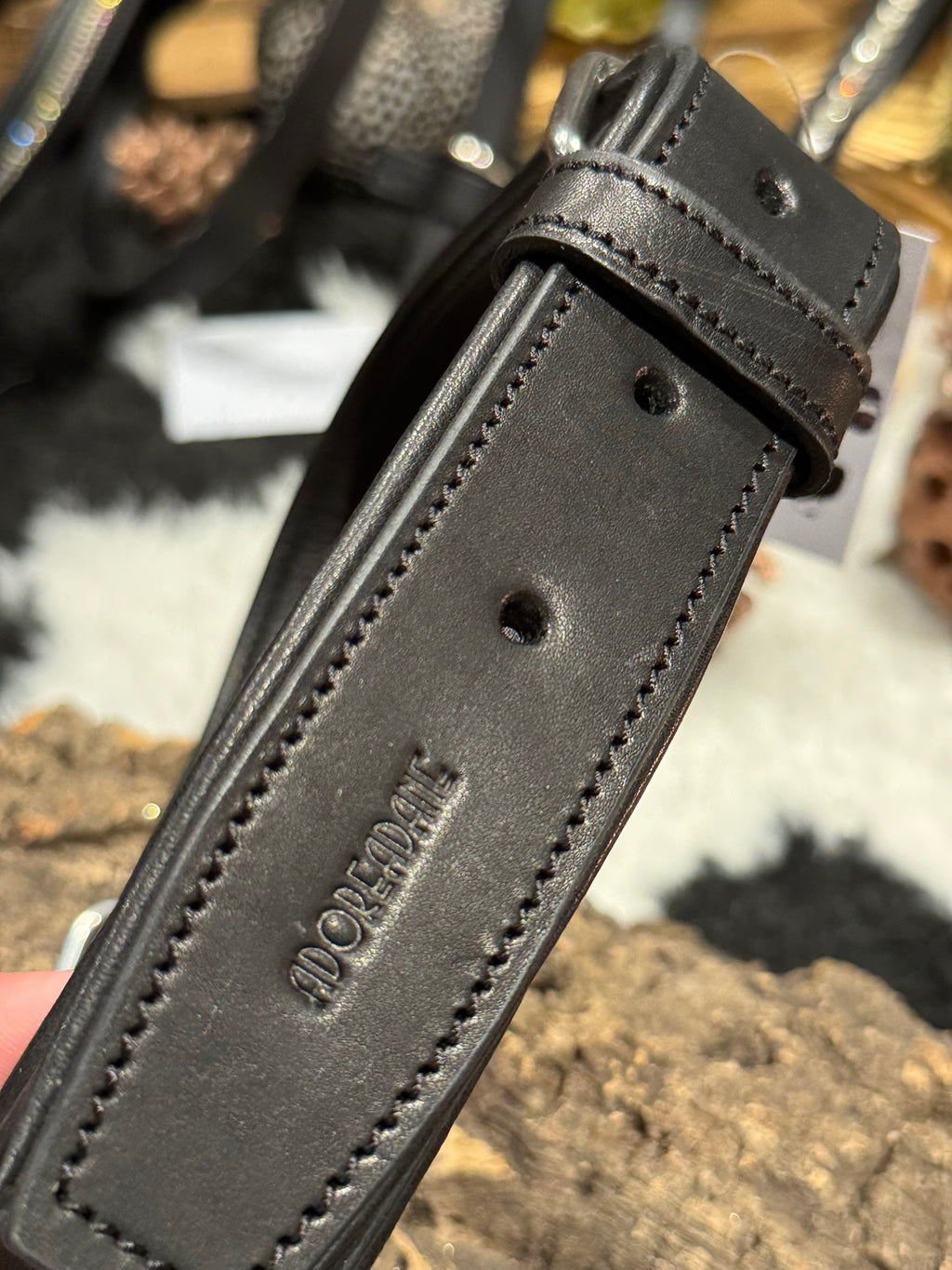 Close-up of a black leather dog collar with stitching detail imprinted with the Adoreadane text logo